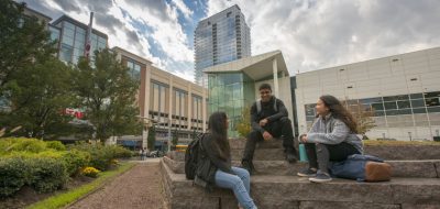Three students sitting on steps at the UConn Stamford Campus.